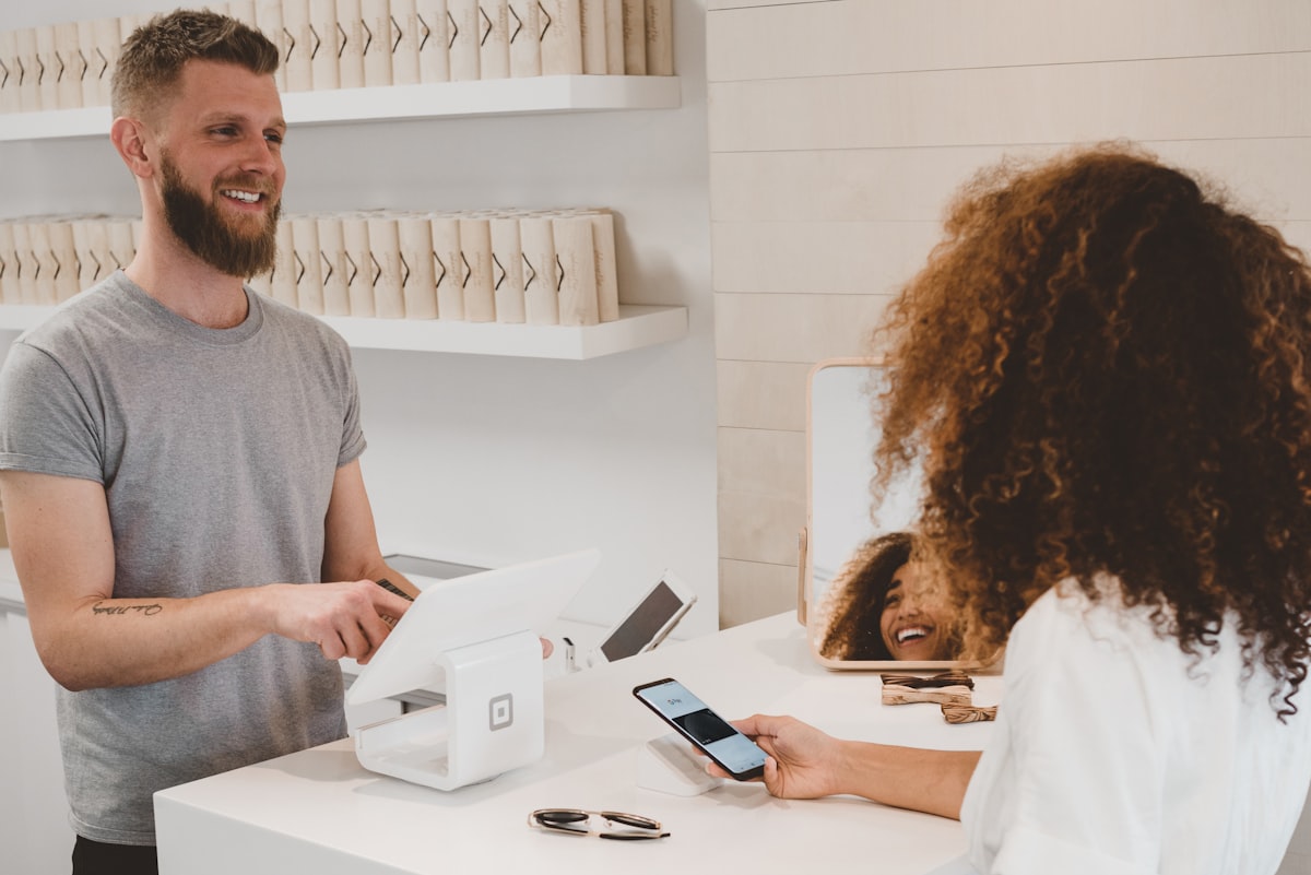 Un vendeur encaisse une cliente qui paie par téléphone